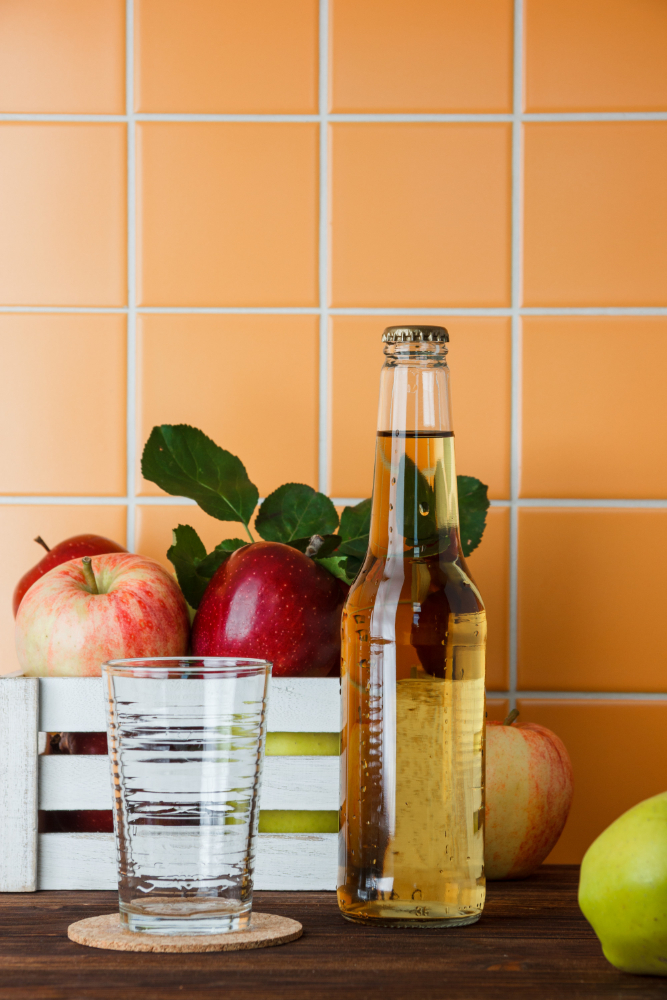 side-view-apples-in-box-with-apple-juice-on-wooden-and-orange-tile-background-vertical-space-for-text (1).jpg